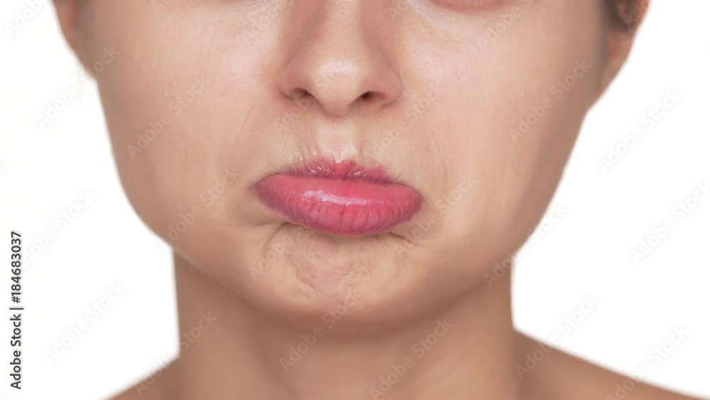 Macro view of adult woman with healthy clean skin and natural makeup twisting her lips being upset or offended over white background. Facial expressions Macro view of adult woman with healthy clean skin and natural makeup twisting her lips being upset or offended over white background. Facial expressions