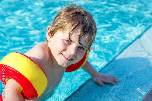 Happy little kid boy having fun in an swimming pool