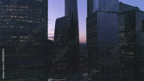 A night drone Aerial Real time video of huge skyscraper building at Moscow-City business centre Skyline, 4K UHD. Camera moving up close to windows.