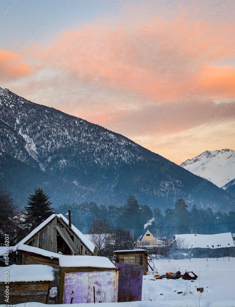 Beautiful winter landscape sunset with snow and village wooden houses