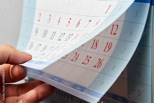 Hand flipping through a wall calendar