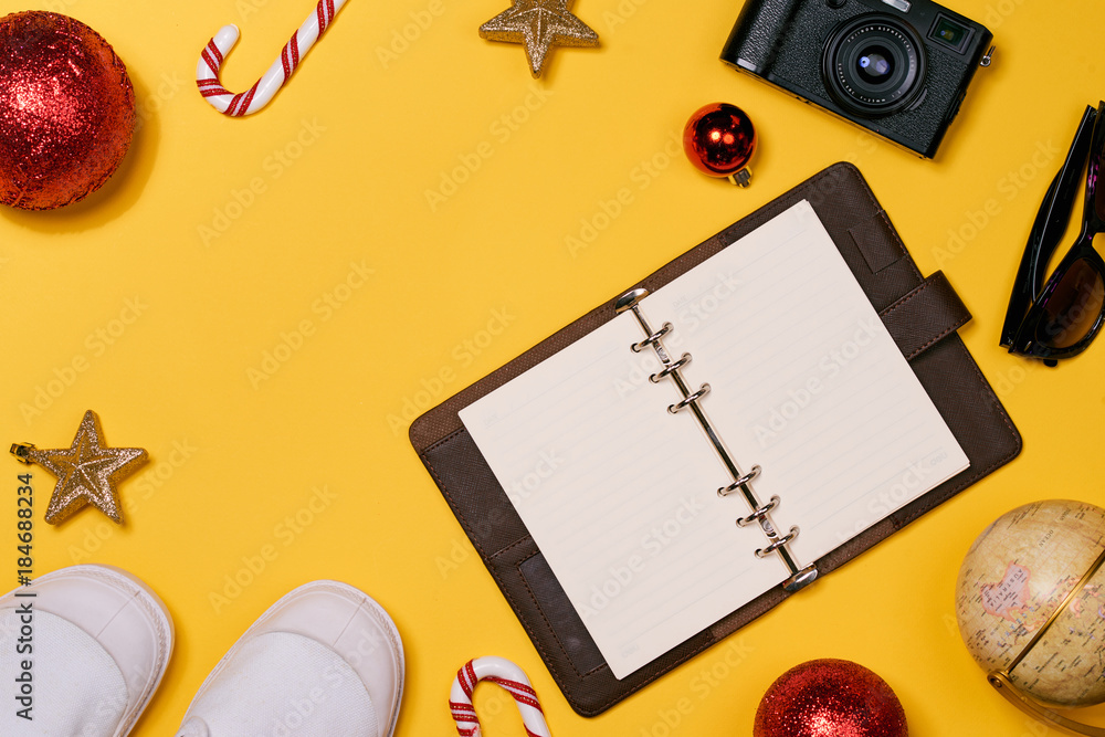 Christmas vacation concept - airplane, camera, notebook, passport on yellow background Christmas vacation concept - airplane, camera, notebook, passport on yellow background