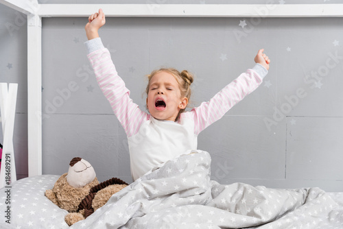 Fototapeta Naklejka Na Ścianę i Meble -  adorable little kid yawning and stretching while waking up