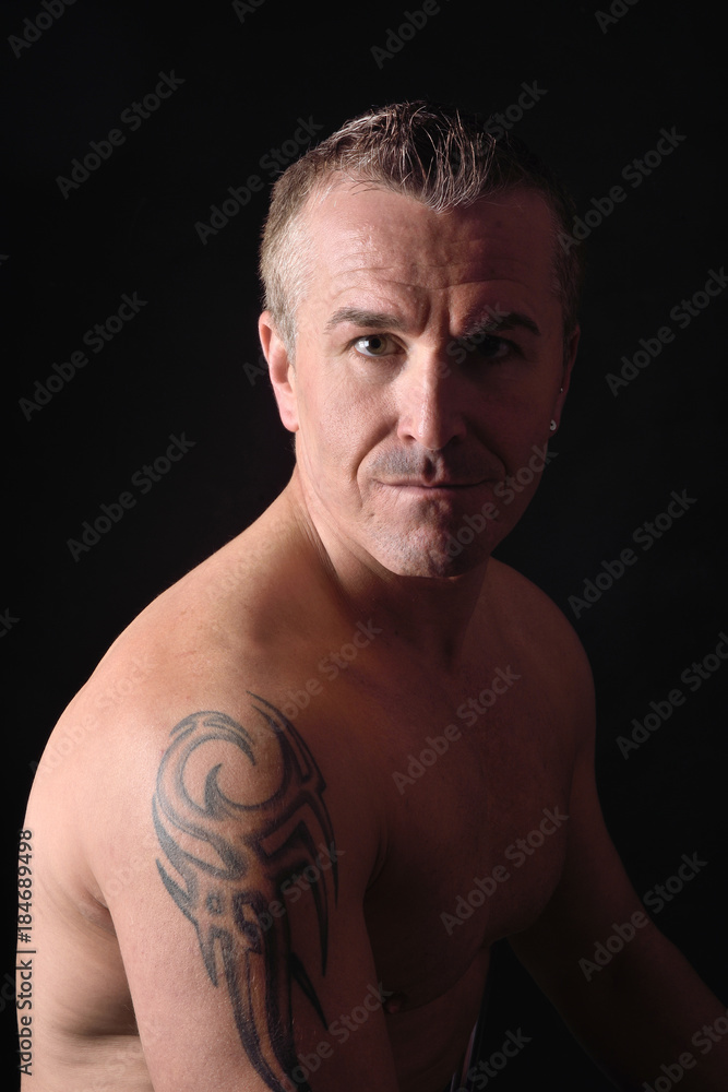 Fototapeta premium portrait of a man with tattoo and black background