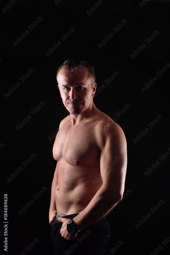 portrait of a man with naked torso on black background