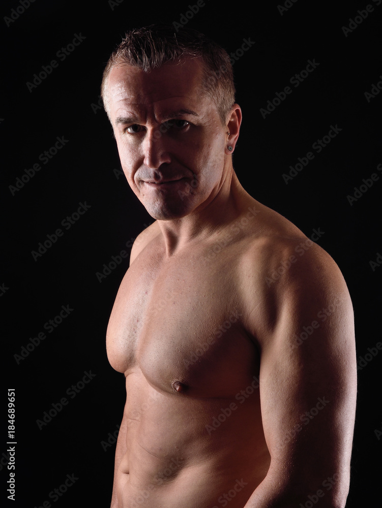 portrait of a man with naked torso on black background