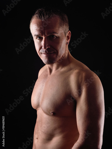 portrait of a man with naked torso on black background