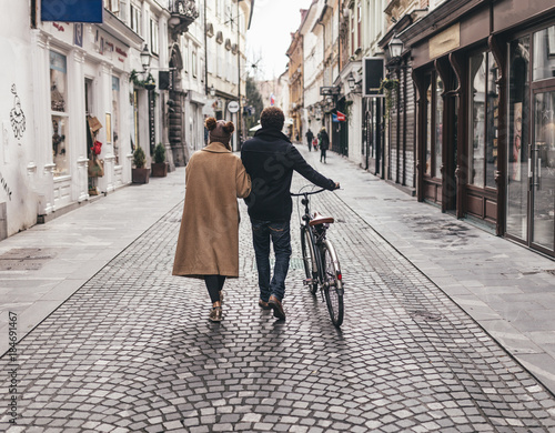 young couple walking on the streets of a lovely little city with a bike
