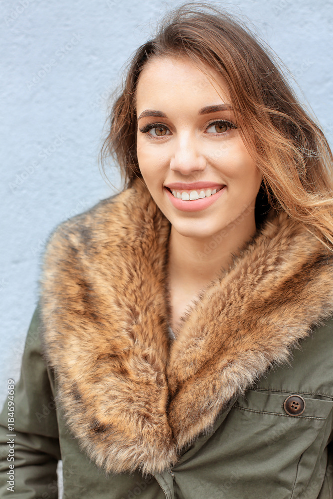 Attractive smiling woman in jacket with fur collar on light background Attractive smiling woman in jacket with fur collar on light background