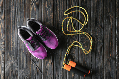 Jumping rope and sneakers on wooden background