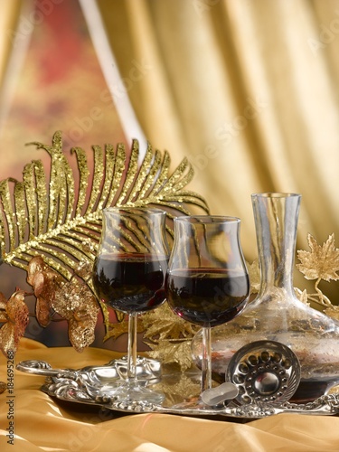 red wine into stem glasses served on a silver tray. decorations on the table are gold coloured