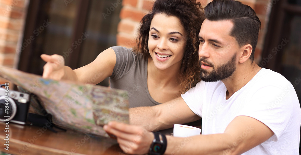 Fototapeta premium Young tourists having coffee at cafe and reading map