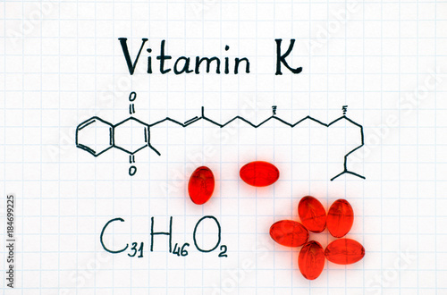 Chemical formula of Vitamin K and red pills. photo