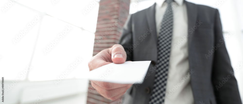Businessman giving a card. Close-up photo in loft office Businessman giving a card. Close-up photo in loft office