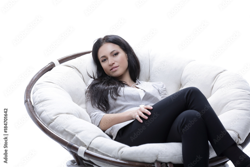 Fototapeta premium Modern young woman sitting in a round cozy soft chair