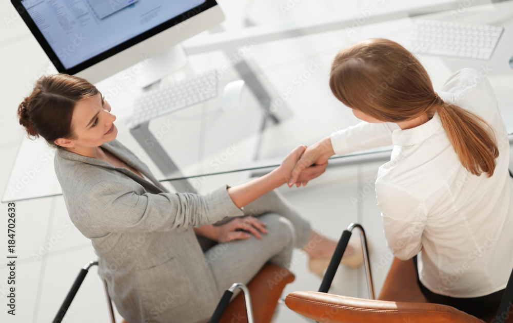 view from the top.business woman shakes hands with the officer sitting near the desktop view from the top.business woman shakes hands with the officer sitting near the desktop