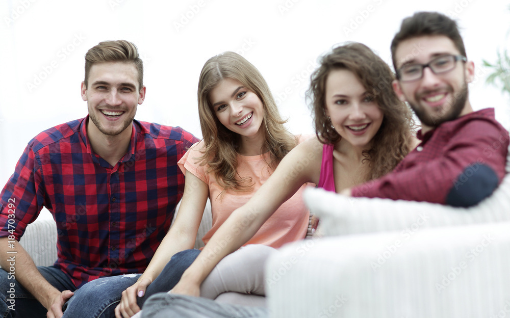 group of cheerful friends sitting on sofa