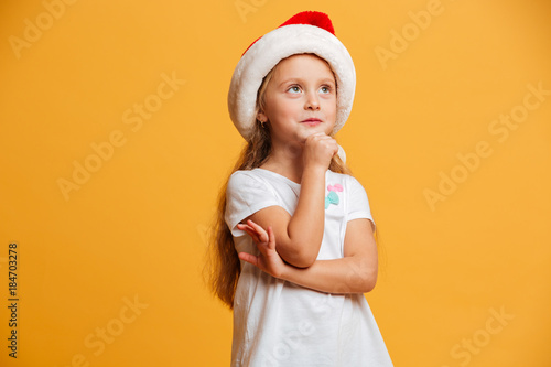 Thoughtful girl standing isolated wearing christmas santa hat. © Drobot Dean