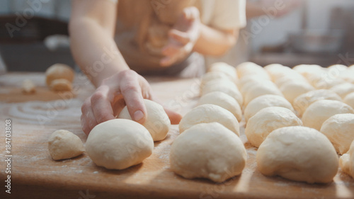 Foto Cooks roll the dough for baking, pieces of raw dough on the wooden Board