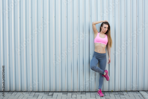 Fitness girl posing on wall background