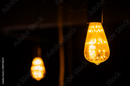 old retro vintage light bulb hanginh from ceiling with back background photo