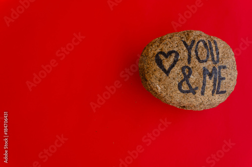 the english writing you and me with a heart drawn on a stone/ the writing you and me with a heart drawn on a stone,indicates the love promise of two lovers photo