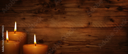 Burning candles in front of rustic wooden wall photo