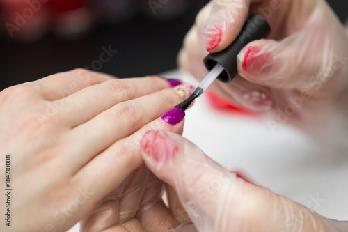 Master applying polish on fingernails on woman