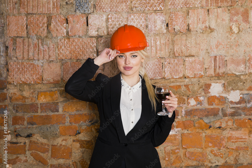 Portrait of architect student or painter with glass of wine and protect helmet wearing. Brick red background.