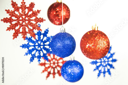 Beautiful Christmas and New Year colorful background. Close up of red and blue shining ornaments hanging on glossy silver ropes isolated on white. Horizontal color phtography.