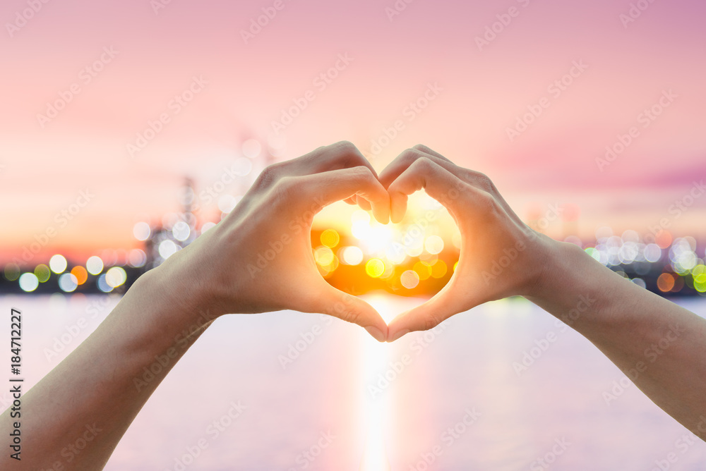Female hands in the form of heart against sunlight with Oil Refinery industry bokeh light in sunset sky, twilight time. Hands in shape of love heart, Love and saving fuel energy concept. Female hands in the form of heart against sunlight with Oil Refinery industry bokeh light in sunset sky, twilight time. Hands in shape of love heart, Love and saving fuel energy concept.