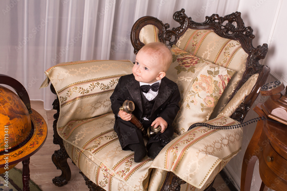 Child in a tuxedo sitting in an office talking on the phone. Child in a tuxedo sitting in an office talking on the phone.
