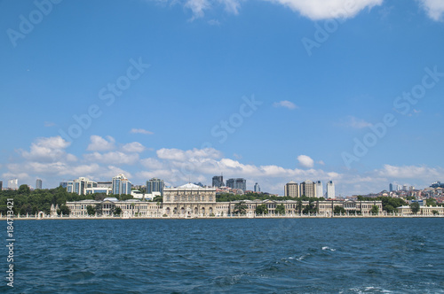 Dolmabahce palace against coastal cityscape with modern buildings under cloudy sky istanbul city