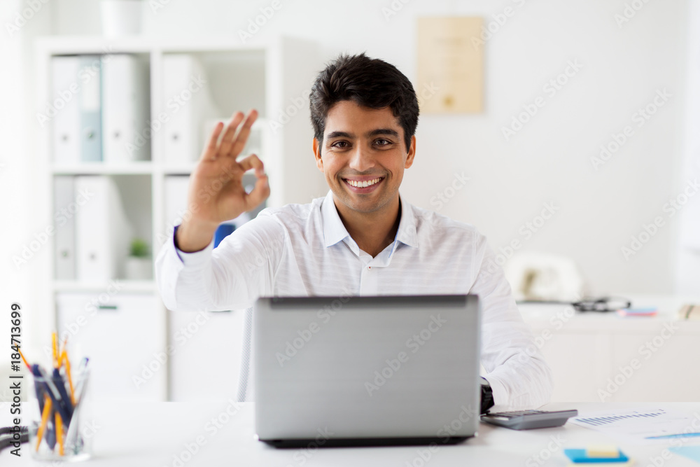 businessman with laptop showing ok sign at office