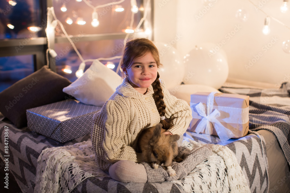 Very beautiful and charming little dark-haired girl in white sweater holds a live rabbit in the interior of the house. New year. Christmas. Hare. Studio. Very beautiful and charming little dark-haired girl in white sweater holds a live rabbit in the interior of the house. New year. Christmas. Hare. Studio.