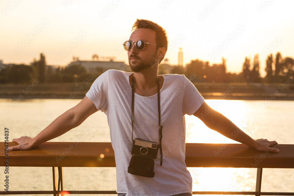 Modern tourist guy enjoying outdoors with retro film camera.