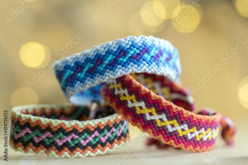 Three handmade homemade natural woven bracelets of friendship in magic christmas lights reflections on background