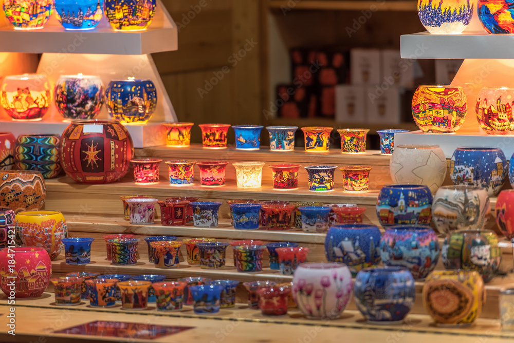 Fototapeta premium Beautiful colorful candlelights with attractive designs offered at a booth on a Christmas market. Concept: holidays, christmas