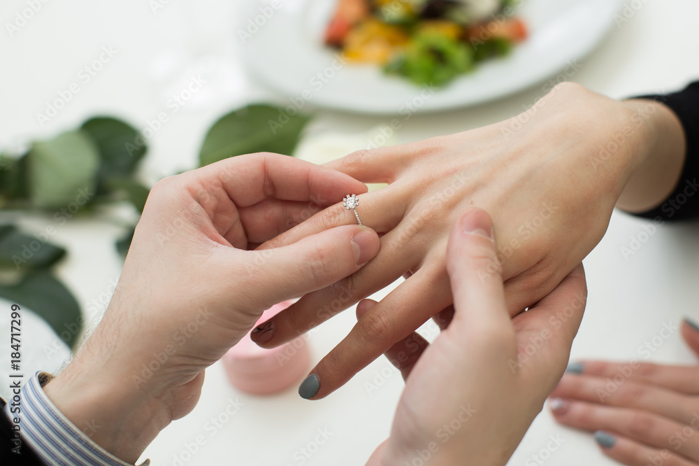 Fototapeta premium Close Up Of Male Hand Inserting An Engagement Ring Into A Finger