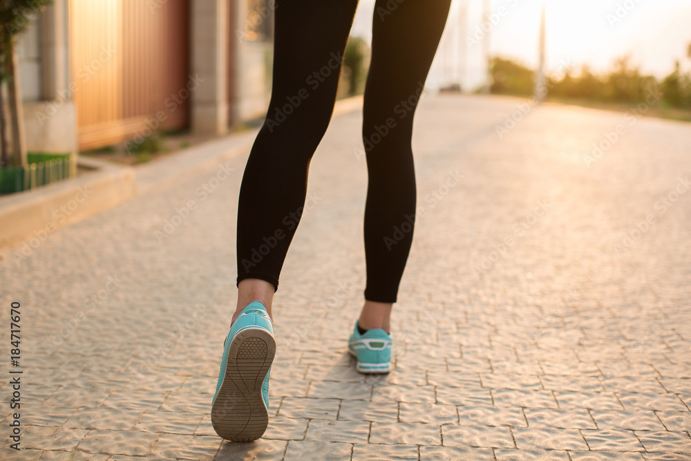 Athlete runner feet running on road closeup on shoe. woman fitness sunrise jog workout wellness concept.