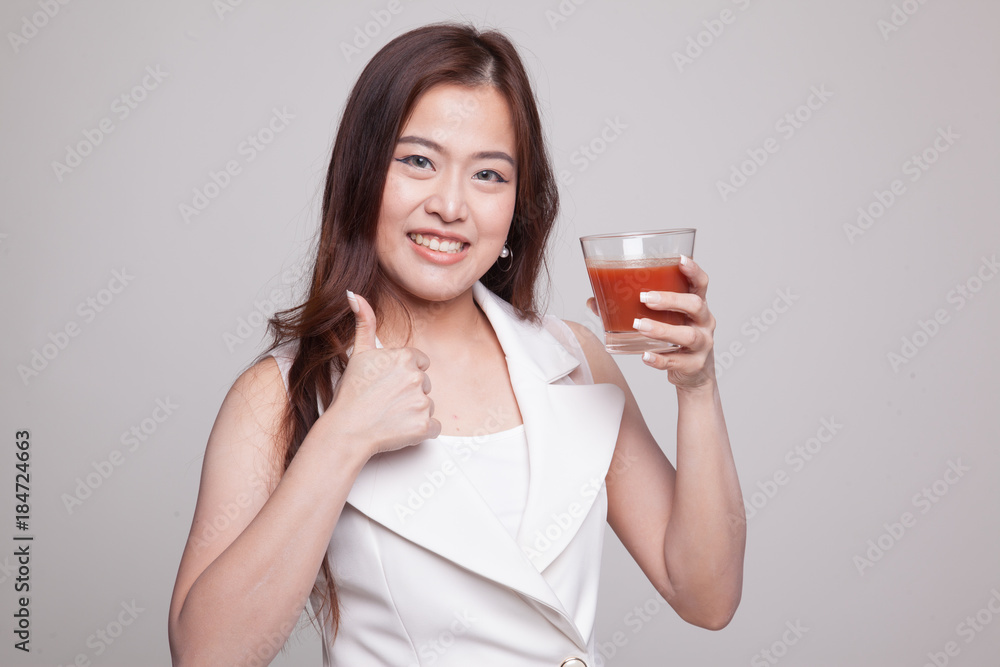 Young Asian woman thumbs up with tomato juice. Young Asian woman thumbs up with tomato juice.