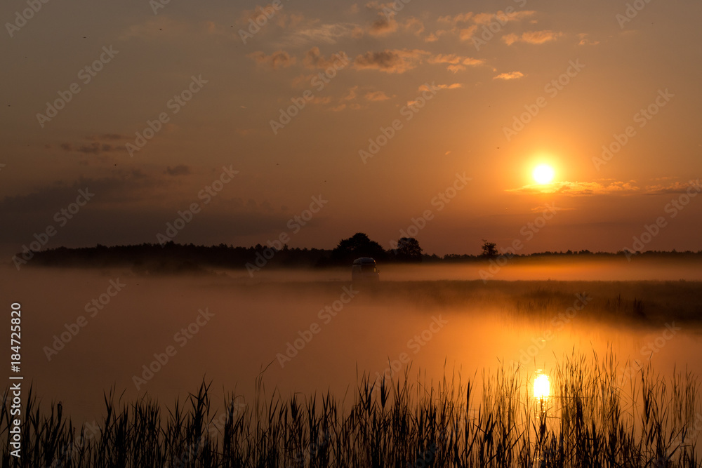 Sunrise by lake at foggy morning