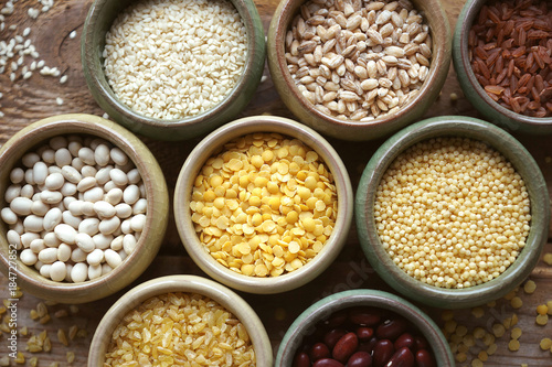 Bowls of various cereals in small containers on a wooden background, Cereal Mix, Beans, sesame, rice, pearl barley, wheat, Closeup, Selective focus