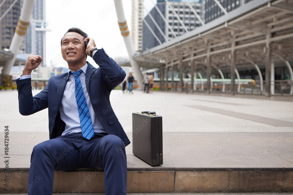 Businessman sitting on stair during callling the phone, with office building background - business success, achievement, and win concepts Businessman sitting on stair during callling the phone, with office building background - business success, achievement, and win concepts