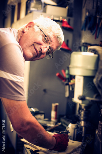 Senior smiling man writing obligations in his notes. Looking at camera.