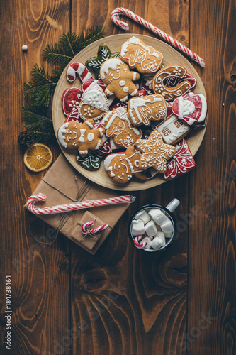 Plate with Christmas cookies on wooden table with cup of hot chocolate and gifts 