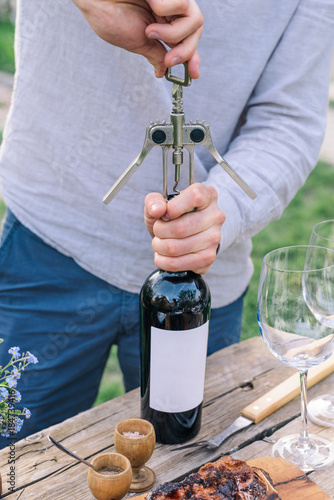 Young man opening a bottle of wine
