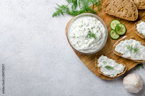 Homemade greek tzatziki sauce in a glass bowl with ingredients a