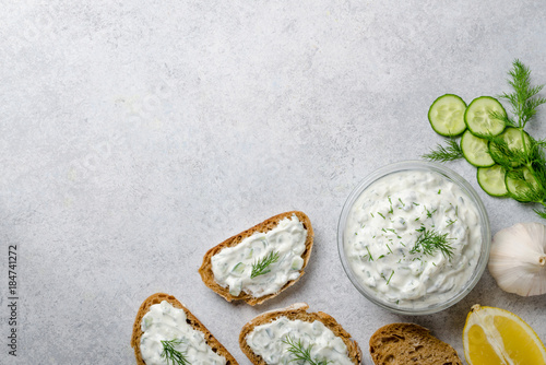Homemade greek tzatziki sauce in a glass bowl with ingredients a