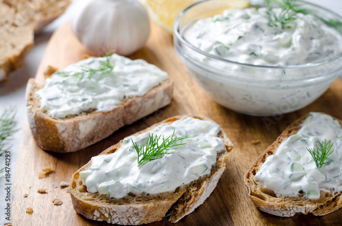 Homemade greek tzatziki sauce in a glass bowl with sliced bread